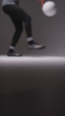 Defocused-Vertical-Video-Close-Up-Of-Female-Footballer-Training-In-Vertical-Video-Studio-Playing-Keepy-Uppy-Kicking-Ball